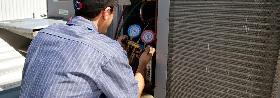 HVAC technician servicing a condenser unit in Maquoketa