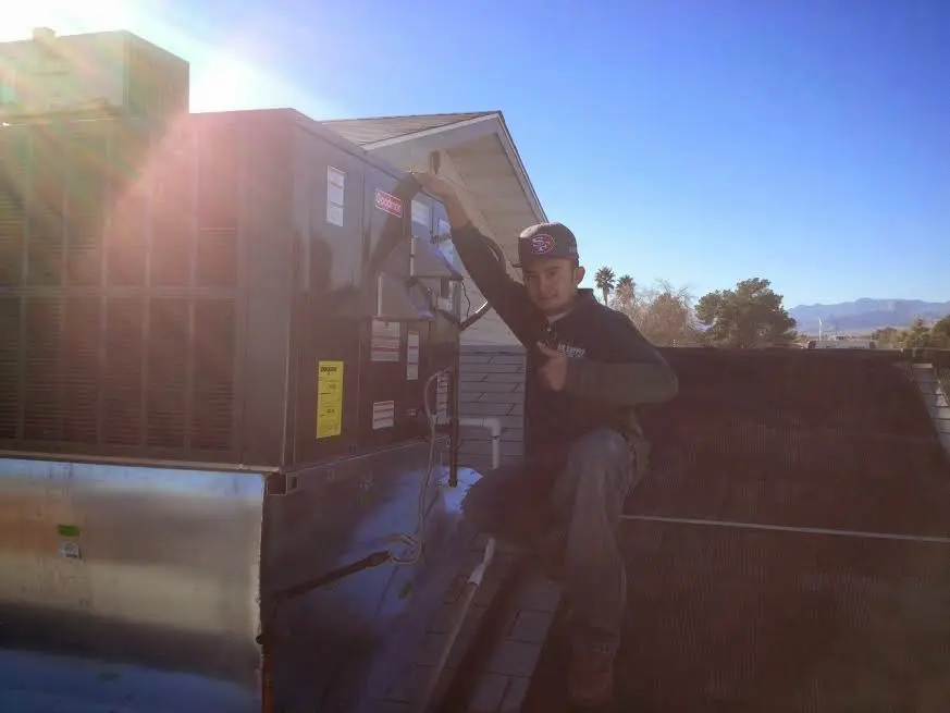 HVAC technician performing AC Tune-Up on a rooftop unit in Maquoketa